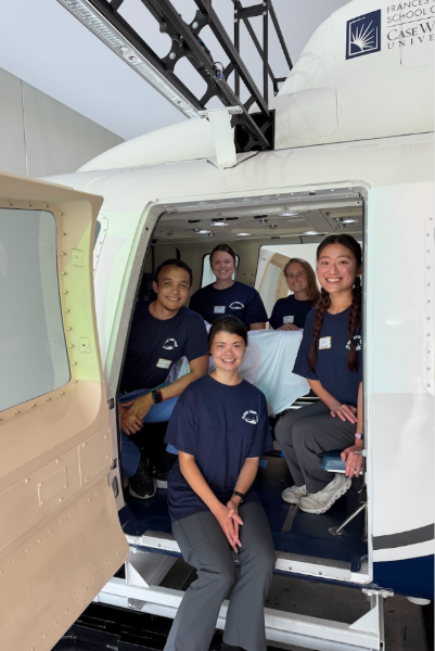 Students sit in the doorway of a helicopter flight simulator.