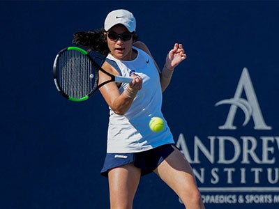 Hannah Kassaie competes in a tennis match with a racket in her hand as the ball approaches