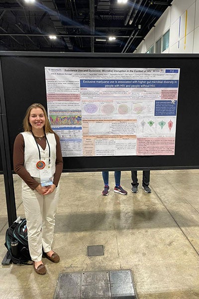 Julie Somogyi poses for a photo next to her poster presentation during a conference