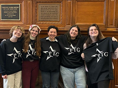 Five members of Players' Theatre Group pose for a photo wearing black T-shirts with PTG in white lettering