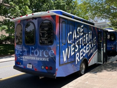 Side view of a CWRU-branded trolley that shows "Case Western Reserve University" and "Be a Force" 