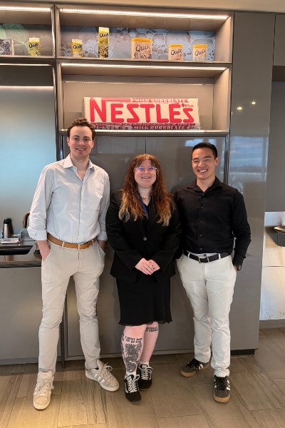 Heather O Brien standing in the center of three interns posing in front of a Nestle sign