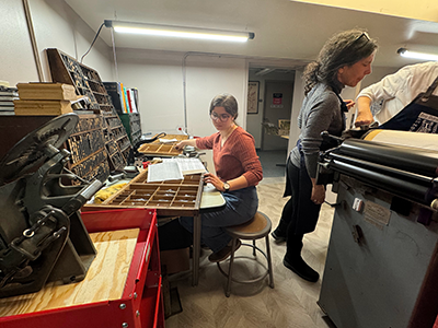 A student sorts letter blocks in the New Guttenberg Annex in Guilford House while Barbara Mann (right) works on one of the printers