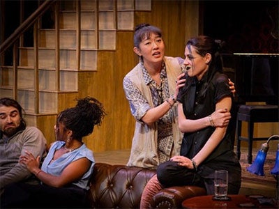 Kashmere Shafik wearing all black in her performance of Loren in Epiphany awhile another actor grips her shoulders