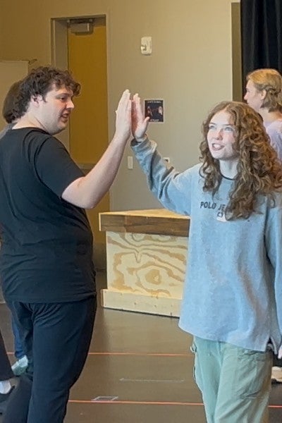 Two students withe their hands held up in the air