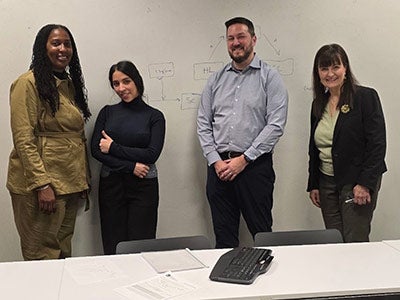 Rania Aljohani stands with three other people in front of a white board