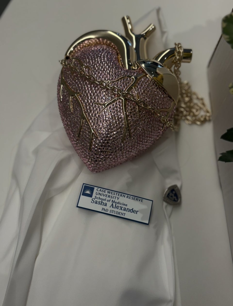 a white coat with Sasha Alexander's nametag and a broach in the shape of an anatomical heart