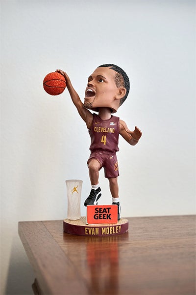 Bobblehead of Cleveland Cavaliers player Evan Mobley holds a basketball aloft, wearing jersey number 4 on a court-themed base beside a small trophy.