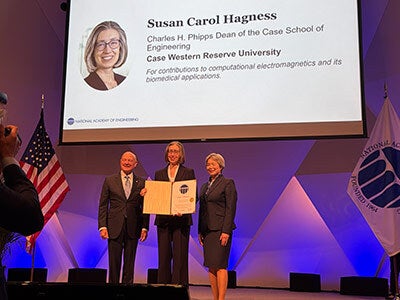 Case School of Engineering Dean Susan Hagness stands on stage with two others at the National Academy of Engineering induction ceremony