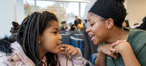 A child points to one of her teeth while a CWRU dental medicine student takes a look in the dental clinic waiting area