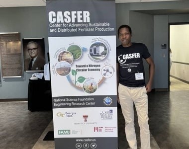Olatunde Akanbi standing in front of his poster