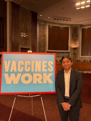 Nikitha Balaji standing next to a sign reading "Vaccines Work"