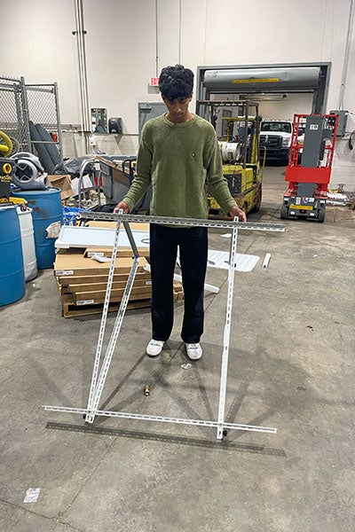 Tanush Anand works on building a metal structure in the lab