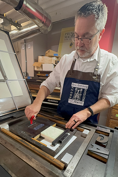Kurt Koenigsberger demonstrates how to operate an antique hand press in the New Guttenberg Annex in Guilford House