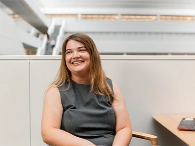 Paris Martin sits in a black sleeveless top in a bright, modern office.