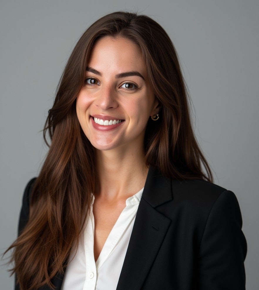 Woman smiling wearing a white blouse and dark jacket. 