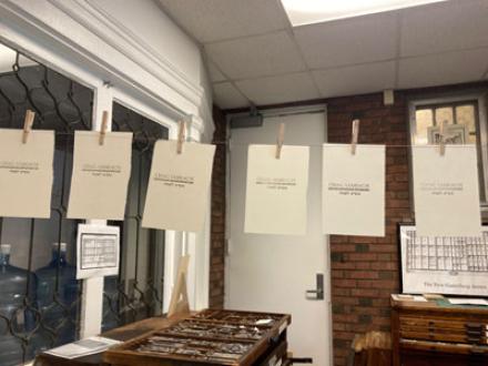 Photo of the Gutenberg Annex, showing printed pages pinned to a line across the room and tools on a surface