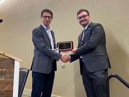 Photo of two men shaking hands as one accepts an award