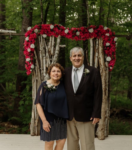 Damiano and his wife standing in front of a floral background
