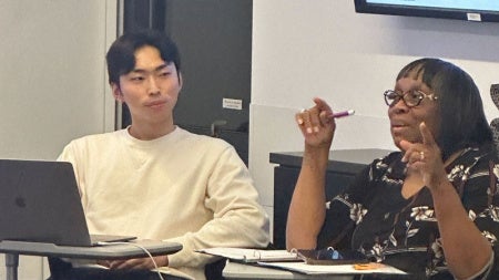 One student looks on as another talks to the class