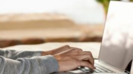 Hands typing on a laptop