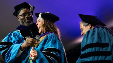 A woman laughing in commencement regalia