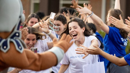 Students rush to high five and clap hands with Spartie