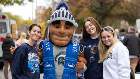Students stand in CWRU gear for a photo with Spartie at homecoming