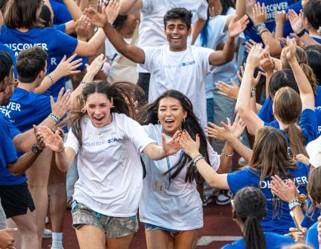 Photo of CWRU Class of 2029 students running through a tunnel of orientation leaders during Discover Week
