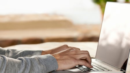Close up photo of hands typing on laptop