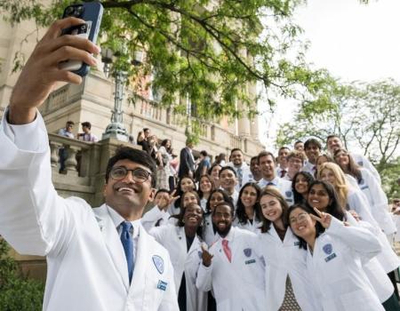 A large group of whitecoat students posing on the steps for a photo