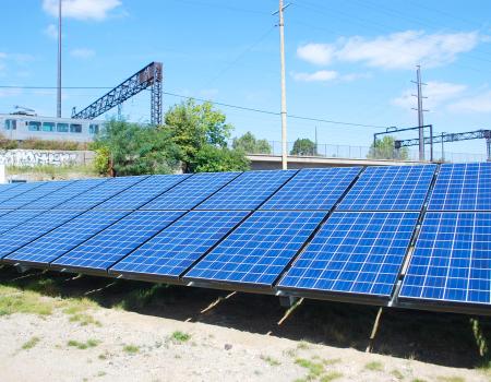 Photograph of rows of solar panels aligned in a field at a photovoltaic power plant in Cleveland.
