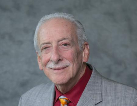Man wearing grey jacket with a orange tie and maroon shirt