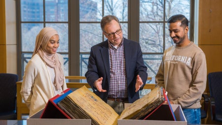 William "Bill" Claspy showcases vintage book with two members of the CWRU community.