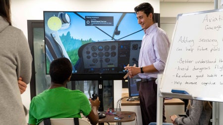 Photo of a PhD leading a demonstration of an aviation haptics program for a high school student