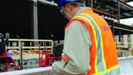 A construction worker signs a beam before the ISEB topping off ceremony.