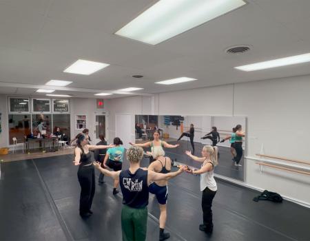Photo of dancers gathered in a circle during a rehearsal