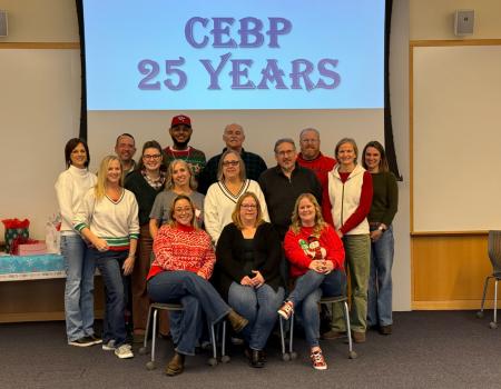 Staff members from the Center for Evidence Based Practices standing under a screen that says "CEBP 25 Years"