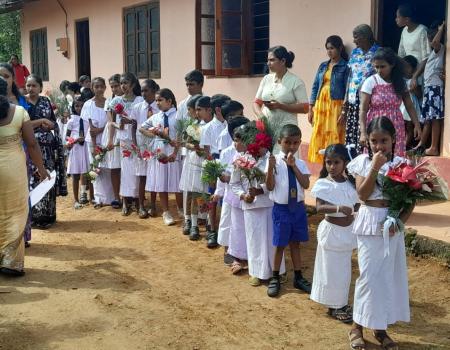Village children of Boralanda standing in front of a building holding flowers