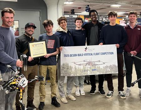 Members of VTOL gather for a photo with their team banner