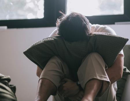 A sad person puts their head in a pillow.