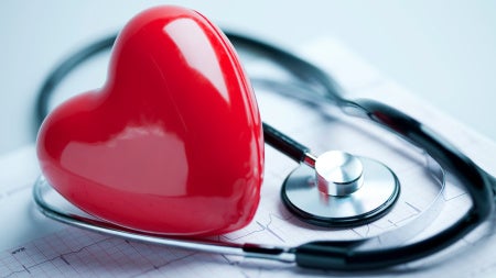 plastic heart laying on top of medical records next to a stethoscope