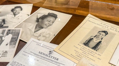 A selection of papers feature photos of Black nurses are spread out in a display case.