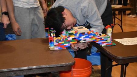 A student tests their lego bridge stability during a 2025 E-Week event