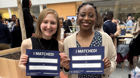 two students smiling together with their match day papers