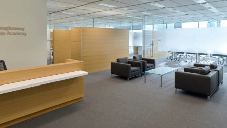 Marian K. Shaughnessy Nurse Leadership Academy lobby with brown desk and black couches.