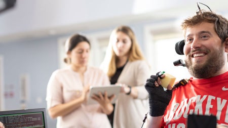 Photo of a man with quadriplegia holding an item with the help of a brain-computer interface