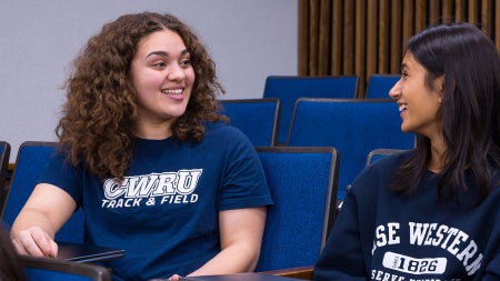 Photo of two CWRU students speaking to each other in a classroom