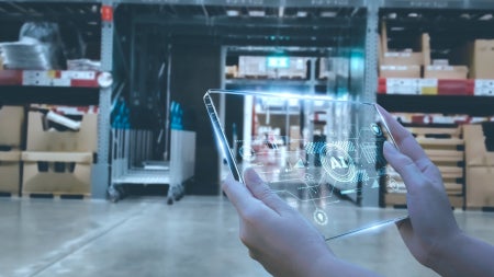 Hands hold a tablet illustrating concept of AI with a background of a warehouse