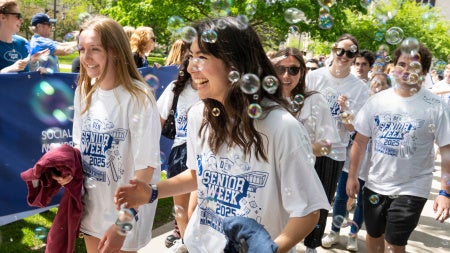 Happy Class of 2025 graduates walk through bubbles at CWRU's annual clap out celebration. 